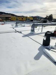 A roof with white flat roofing and wires.